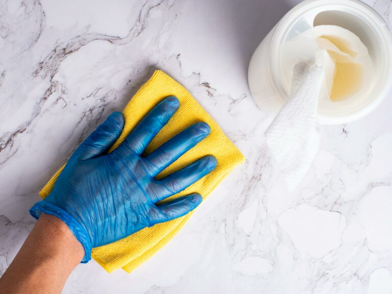 Nettoyage professionnel des surfaces avec gants en nitrile, chiffon jaune et produit de nettoyage.