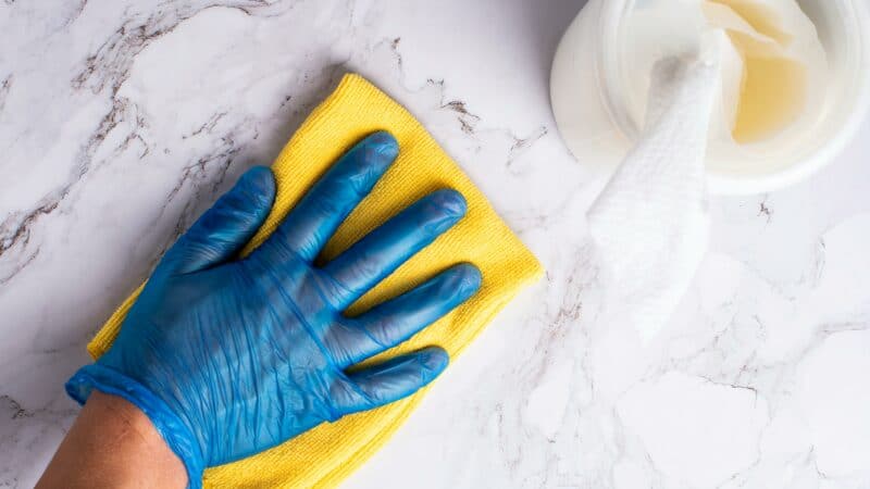 Nettoyage professionnel des surfaces avec gants en nitrile, chiffon jaune et produit de nettoyage.