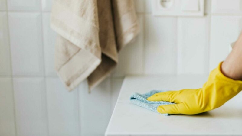 Nettoyage professionnel de surfaces avec gant en caoutchouc jaune et chiffon microfibre.